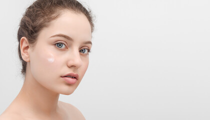 Portrait of a beautiful blue eyed young woman with smear of a face cream on her cheek. Banner with copy space on the right.