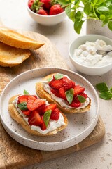 Bruschetta with goat cheese or ricotta witn strawberry and basil. Appetizer with berries. Summer healthy breakfast. Selective focus.