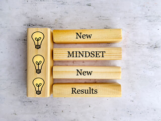 New mindset new results quote on wooden cubes with yellow  light bulbs 