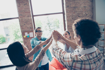 Photo of group positive friendly partners hands palms give high five each other congratulate indoors