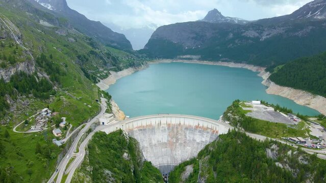 Water dam and reservoir lake aerial drone footage in French Alps mountains generating hydroelectricity. Low CO2 footprint, decarbonize, renewable energy, sustainable development. 4K 60fps video.