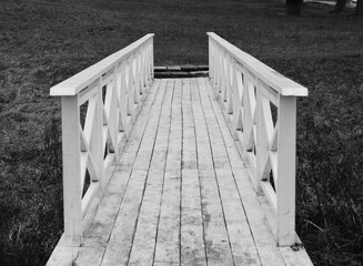 Obraz premium Durable Old wooden white bridge on a grass background, black and white photo
