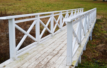 old wooden white bridge on grass background in autumn