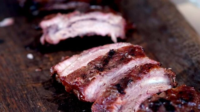 Tasty and delicious barbeque pork ribs grilled, fried outside, outdoor, on wood charcoal grill. national barbeque day. street food. BBQ cooking. An unrecognizable woman takes a piece and eats.