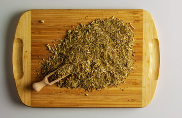 Dry yerba mate leaves, traditional drink of Argentina, on a wooden board and a wooden spoon...