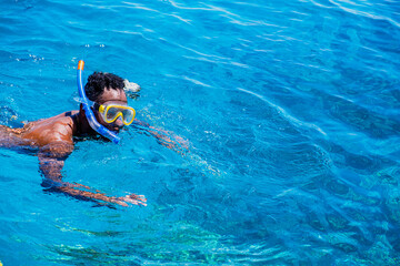 African American boy with diving mask swimming and snorkeling on a beautiful beach enjoying the summer