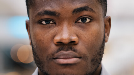 Male portrait of close-up serious african american man looking in camera confident young businessman freelancer stands indoors professional model male posing sad guy student with deep gaze dark eyes