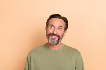 Obraz premium Portrait of satisfied minded man toothy smile look interested empty space isolated on beige color background