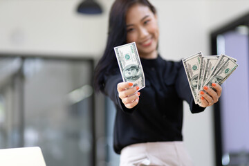 Cheerful beautiful woman holding cash banknote happily counting money.