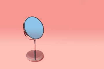 Round desk mirror on leg with stand for makeup on pink background with copyspace