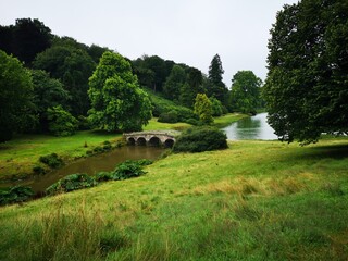 Lake crossed by bridge amidst grass fields and trees
