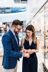 Beautiful couple enjoying in shopping at modern jewelry store. Fashion style and elegance concept.