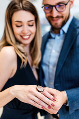 Beautiful couple enjoying in shopping at modern jewelry store. Close up shot of woman's hand with gorgeous expensive ring and bracelet.