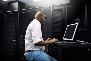 Making sure your servers are protected. Cropped shot of an IT technician using a computer while working in the server room of a data center.