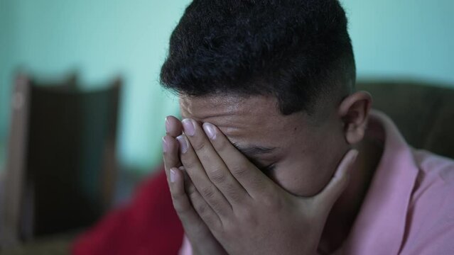 One anxious hispanic young man covering face with regret emotion