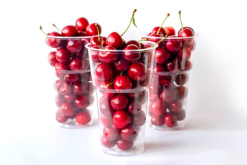 Ripe cherry in a plastic cup on a white background.