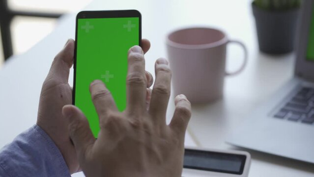 A man holds a smartphone with both hands. Press your finger and slide the green screen chroma button. click on the application icon swipe up 4k video