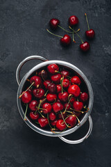 Cherry. Sweet Cherries with drops in colander on dark stone concrete background. Ripe Sweet Red Cherries.