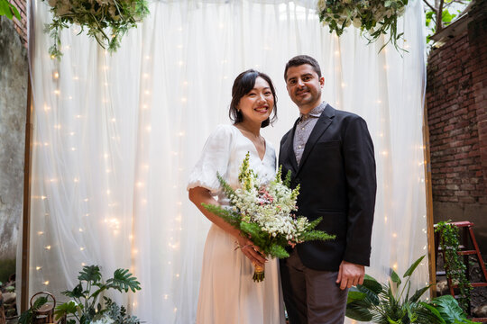 Newlywed multiethnic couple with bouquet of flowers
