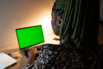 African American female working on laptop with green screen