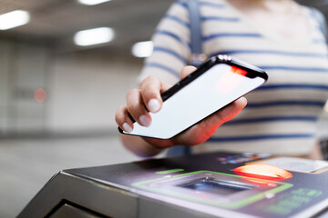 Cropped shot of young Asian woman scanning QR code, checking in at subway station, making a quick...