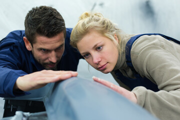 Fototapeta premium male and female mechanics inspecting surface of panel