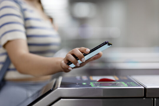 Cropped shot of young Asian woman scanning QR code, checking in at subway station, making a quick and easy contactless payment for subway ticket via smartphone