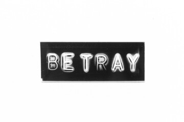 Black color banner that have embossed letter with word betray on white paper background