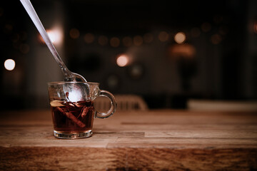 spoon stirring a cup with coffee combination on a wooden board and a dark background with dim lights