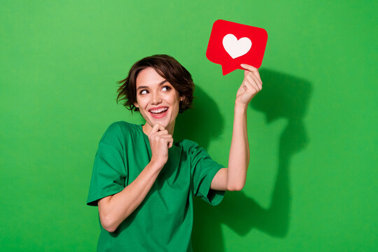 Photo of charming dreamy woman wear casual t-shirt arm chin looking heart like sign empty space isolated green color background