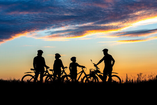 Silhouette four 4 cyclist at sunset. family on cycle ride in countryside