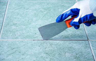 Man uses Trowel to remove old grout. Replace the old grout between the tiles. Mining tiles for...