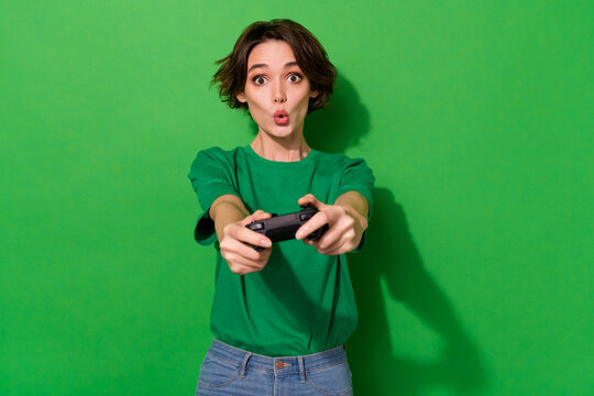 Photo of sweet impressed lady wear spring outfit big eyes having fun playstation isolated green color background
