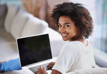 This site is awesome. Over the shoulder shot of a young woman using a laptop at home.