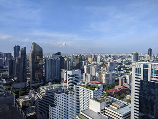 Fototapeta premium An aerial view of city landscape view of Bangkok,Thailand with high rise modern buildings in metropolitan area, skyscraper scenic and blue sky during the day time 