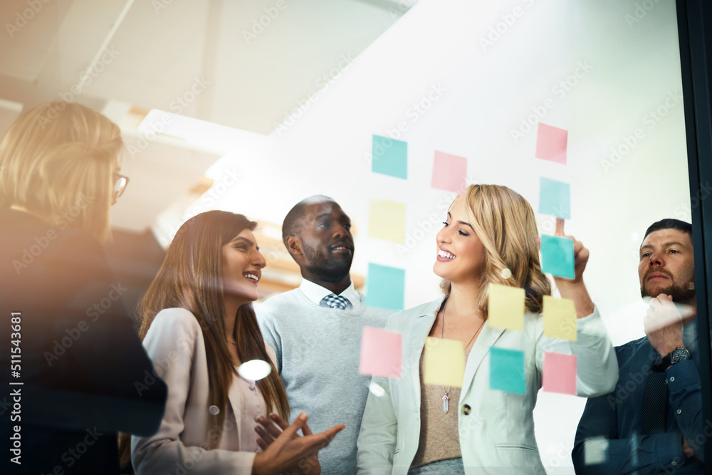Poster marketers flexing their mental muscles. shot of a group of businesspeople arranging sticky notes on 