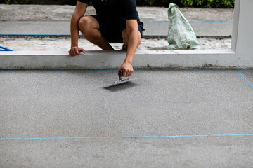 man working on explsed aggregate finish the front of the house