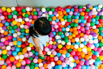 Fototapeta na wymiar Little children playing with colored plastic balls on the playground
