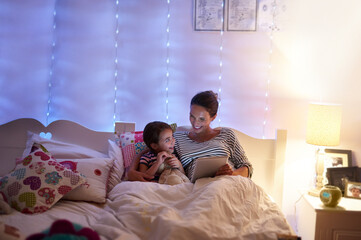 Can we read another one, Mom. Cropped shot of an attractive young woman reading her daughter a bedtime story.