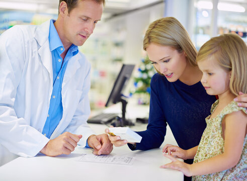 This Is Just What She Needs. A Pharmacist Giving Medication To A Mother And Daughter.