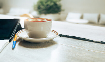 Close up view, latte coffee in ceramic cup with  tablet computer and pen  on wooden table, Relax in cafe after work, Retro stly and vintage color tone