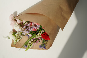 Big bouquet of different colored flowers on a white background in a paper package with space for text