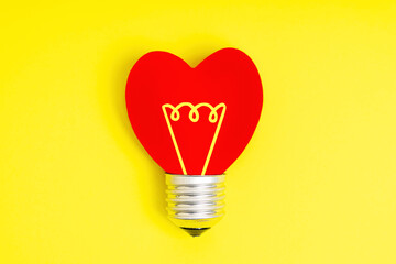 Heart shaped lightbulb symbol on yellow background