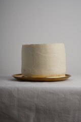 Beautiful white vegan wedding cake with cream without decoration stand on a table with a bowl for text or decor. Confectionery, women's business