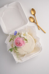 Top view of small elegant white icing cake on packages with fresh flowers for decor wedding cake