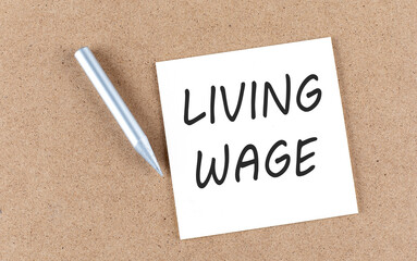 LIVING WAGE text on a sticky note on cork board with pencil ,