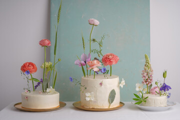 Three  white wedding cake with mixed fresh flowers decorations on the table. Perfect wedding dessert composition