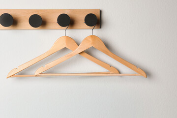 Rack with empty wooden clothes hangers on white wall - obrazy, fototapety, plakaty