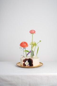 White cake with a chocolate cut on a gold plate on a white table