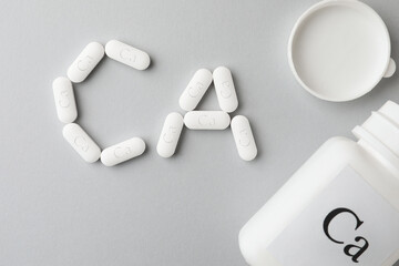 Calcium supplement pills and jar on light grey background, flat lay